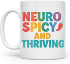 White ceramic Neurospicy and Thriving mug with rainbow lettering and a red chili pepper, handle on the left