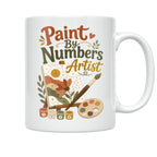 White Paint By Numbers Artist ceramic mug with a floral canvas, paintbrushes, palette and numbered paint pots, opposite-side mug view